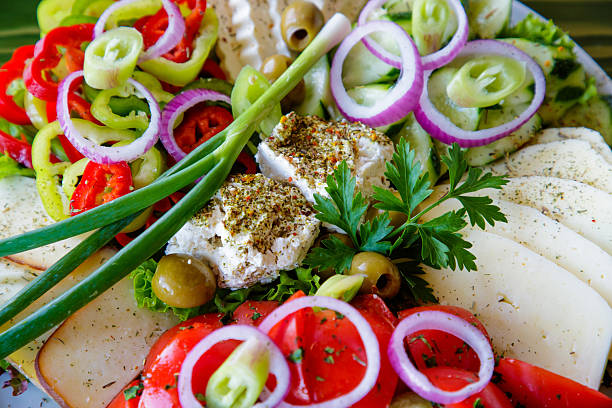 Glass jar with tasty feta cheese in olive oil with olives, spice and pepper on table, with tomatoes, parsley and bread for tasty lanch, closeup