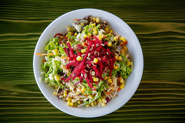 Mixed vegetable vitamin salad with lettuce, beetroot, onion, pepper, corn and carrot, served in bowl on the table, directly above