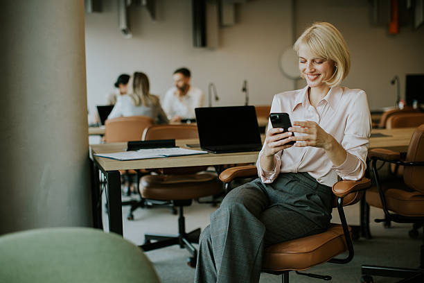 istock Woman checking her phone while sitting in a modern office environment during the day 2249308797