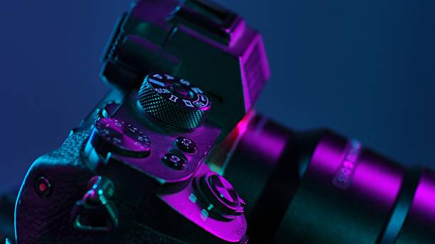 Detailed view of a camera under vibrant neon lighting, showcasing buttons and dials with artistic effect.