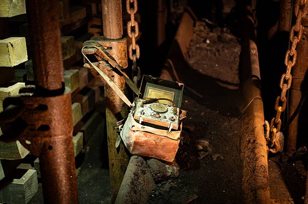 Portable mining gas detector (likely for methane, oxygen) sits in its leather case, hanging from rusty metal and wooden supports