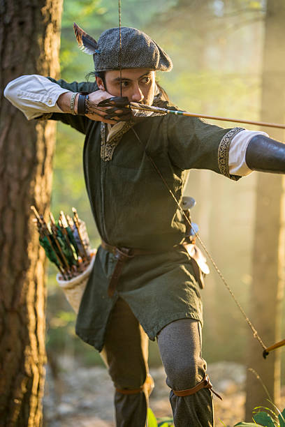 istock Young Medieval Archer Focused on Target Practice in Sunlit Forest 2249311163