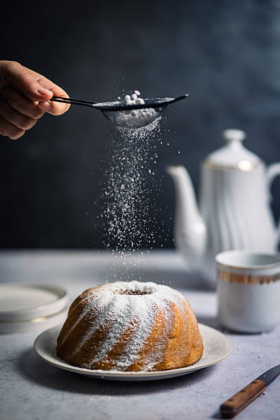 istock A woman sprinkles powdered sugar over a Bundt cake. 2249311279