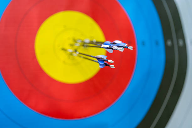 Multiple arrows successfully hitting the bullseye of a colorful archery target, displaying precision and accuracy in the shot placement.