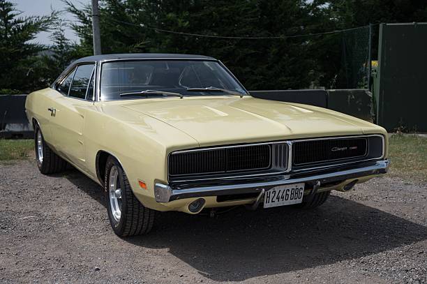 Osona, Spain – June 14, 2025: Front view of a classic American muscle car, a pale yellow 1969 Dodge Charger B-Body, featuring a black vinyl top and a distinctive hidden-headlight