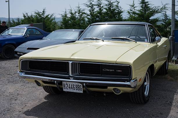 Osona, Spain – June 14, 2025: classic American muscle car, a pale yellow 1969 Dodge Charger B-Body, featuring a black vinyl top and a distinctive hidden-headlight grille.