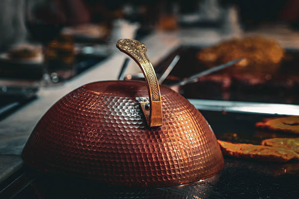 This image showcases traditional copper kitchen utensils used in Turkish and Middle Eastern cuisine, arranged on a rustic wooden surface in Mardin's old market. These handmade items reflect regional culinary practices and artisanal metalwork from southeastern Turkey.