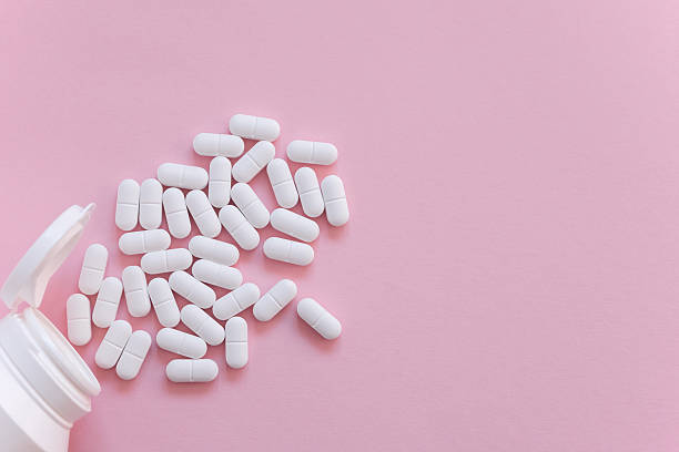 istock White tabletts or pills on the pink background with place for text. 2249313789