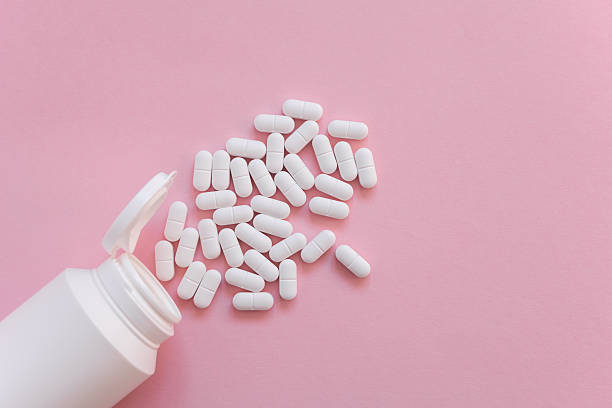 istock White tabletts or pills on the pink background with place for text. 2249313790