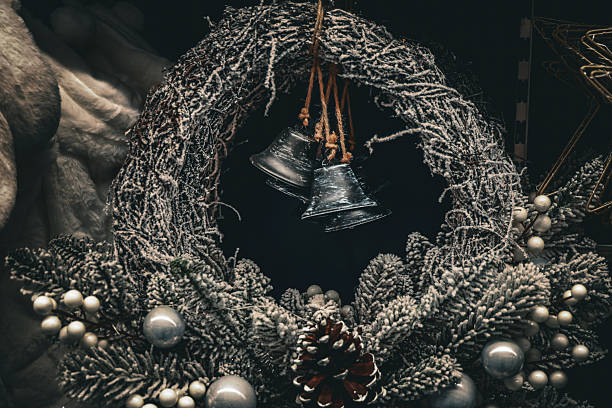 A beautifully frosted Christmas wreath adorned with pine cones, silver ornaments, and hanging bells, captured in rich detail. The wintery textures and festive tones create a warm holiday atmosphere, perfect for seasonal design, decoration, or Christmas-themed creative projects.