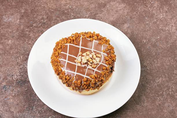 Minimalist food photo of a caramel-topped donut placed on a clean white plate against soft textured background.