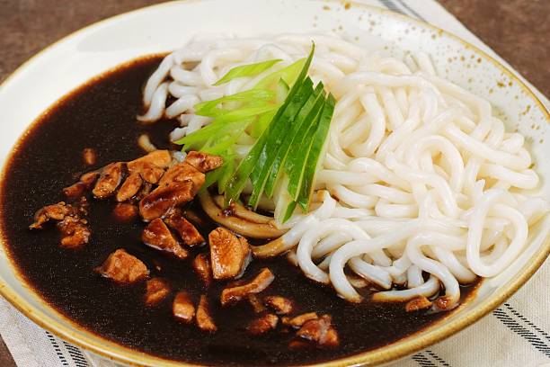 Close-up view of jajangmyeon noodles served with rich black bean sauce and cucumber garnish for a delicious Korean meal.