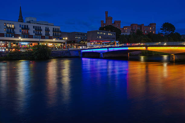 Inverness castle and city lights illuminating the riverside architecture, spanning across the river ness with colorful bridge reflections at twilight, showcasing urban beauty