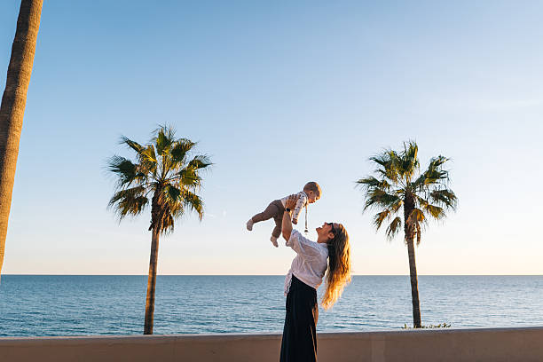 Mother holds baby son on seaside