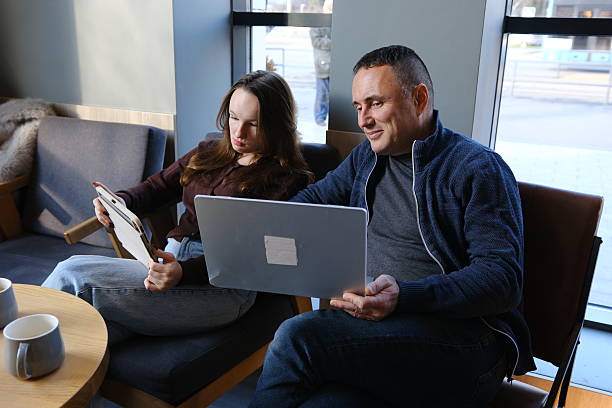istock Smiling team professional employees working together on computer discussing online technology data solutions at work. Two young busy diverse coworkers business people using laptop at office meeting. 2249319450