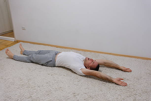 istock Man stretching his arms up and legs down while lying on the floor 2249319809