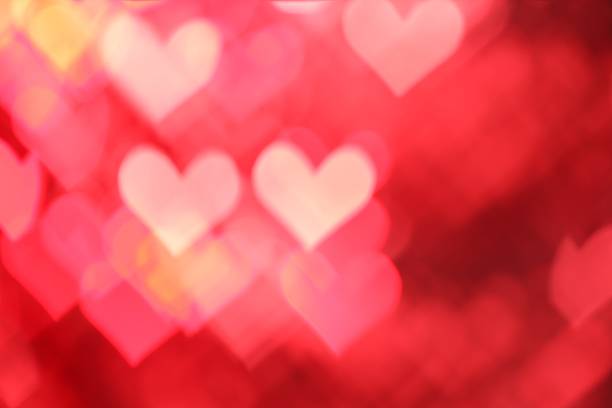 Romantic decor. Blurred view of heart shaped lights on red background, bokeh effect