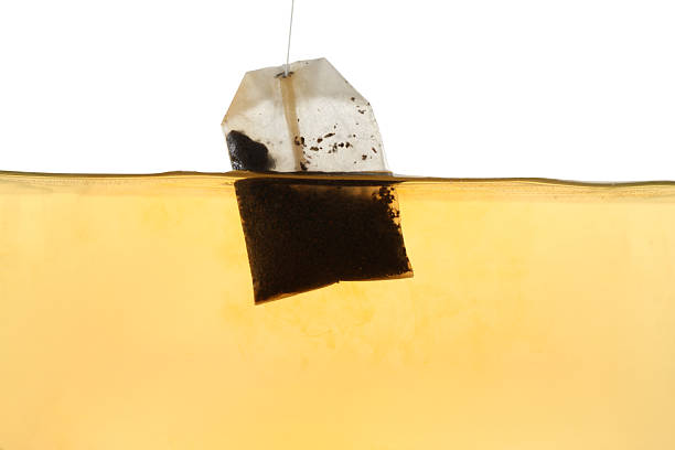 istock Putting tea bag into glass cup on white background, closeup 2249322469