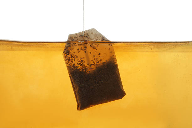 istock Putting tea bag into glass cup on white background, closeup 2249322474
