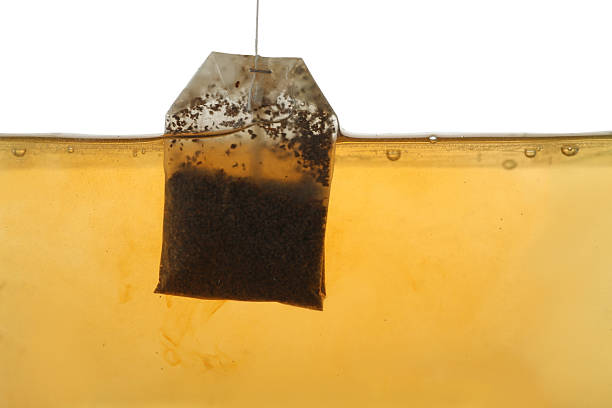 istock Putting tea bag into glass cup on white background, closeup 2249322483