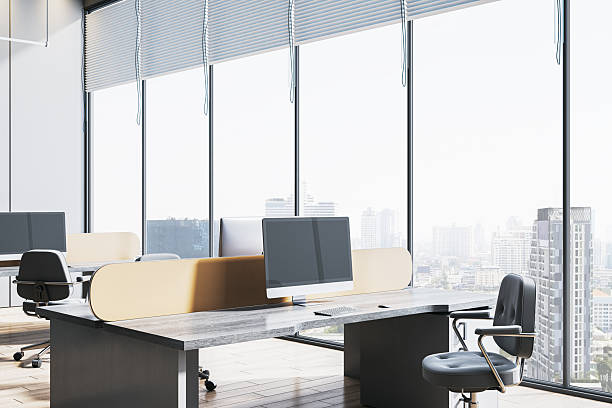 istock Modern empty office with large glass windows, city view, sleek desks, computer monitors, and ergonomic chairs in soft natural daylight. 3D Rendering 2249322786