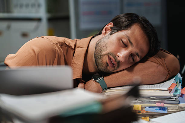 istock A tired businessman sleeps on paperwork at his desk during a late-night workload after becoming overworked and exhausted. 2249322896