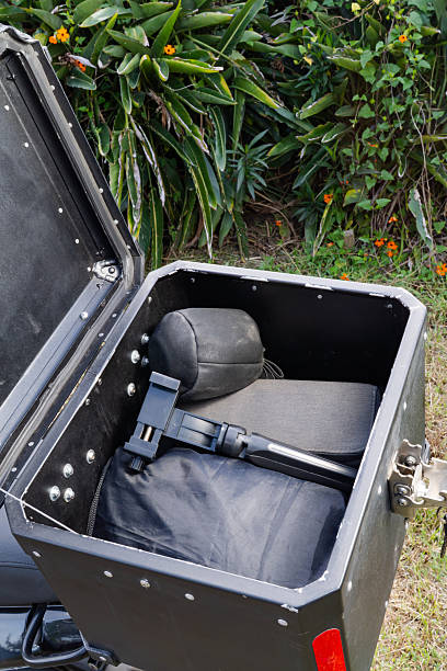 istock Open motorcycle top case with padded backrest and folded gear in garden setting 2249323911