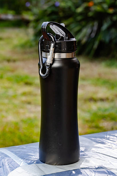 istock Black reusable water bottle with carabiner resting on plastic-covered surface in outdoor setting 2249324050