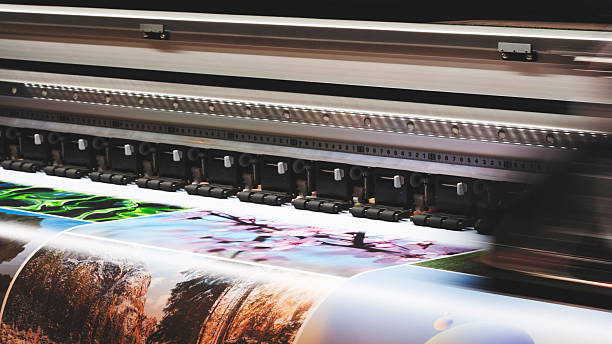 istock A moving working industrial wide format printer prints a color picture on paper. 2249328994