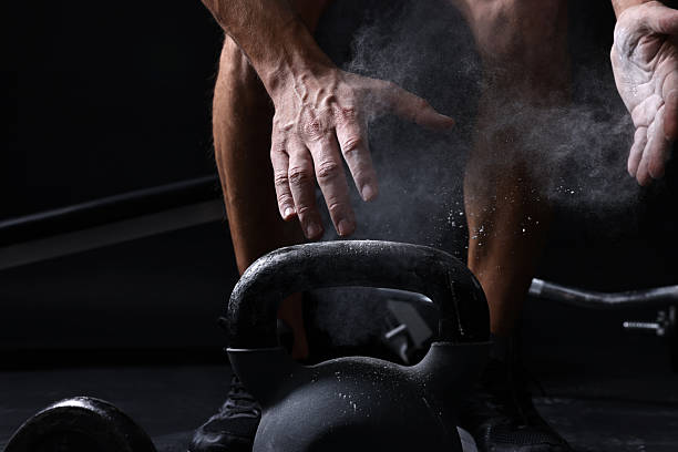 istock Man clapping hands with talcum powder before training with kettlebell on black background, closeup 2249329101