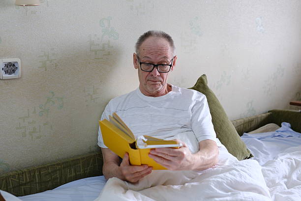 istock old Man reading bed Old man reads a book before going to bed 2249330717