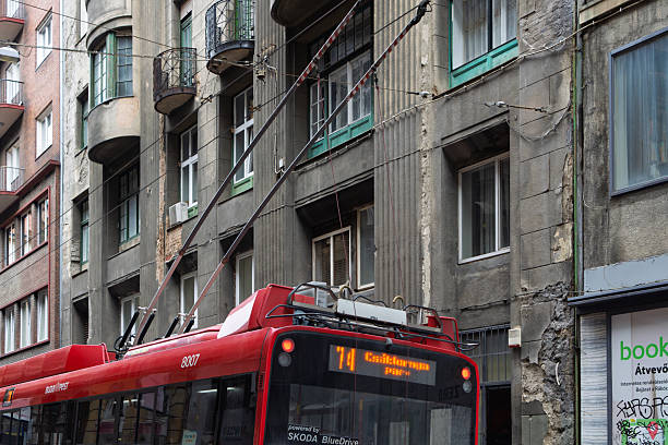 Budapest, Hungary, May 2025Trolley bus with overhead link to electric power lines. Travelling between Soviet era apartment blocks in a narrow street.