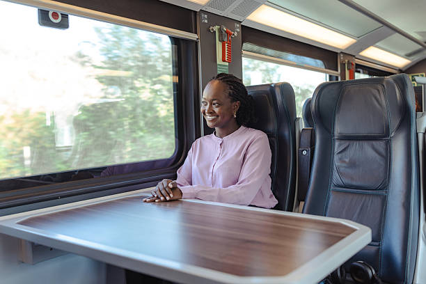 istock Young woman sits at a train table, smiling during a travel work session 2249336571