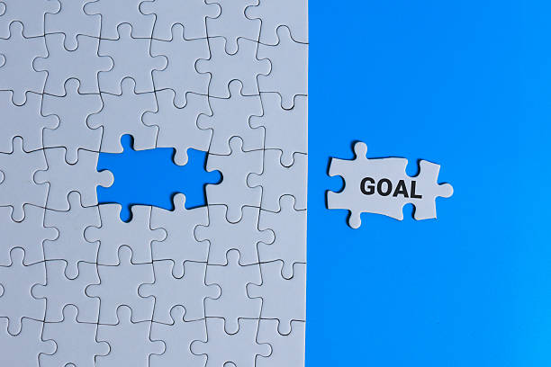 istock White puzzle with a missing piece on a blue background, with a separate piece labeled ‘GOAL’ 2249338142