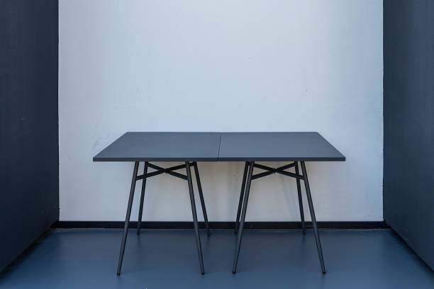 A simple yet elegant room featuring a sleek black table on a gray floor, set against white walls. The minimalist design emphasizes clean lines and modern aesthetics, ideal for contemporary interior spaces or product showcases.