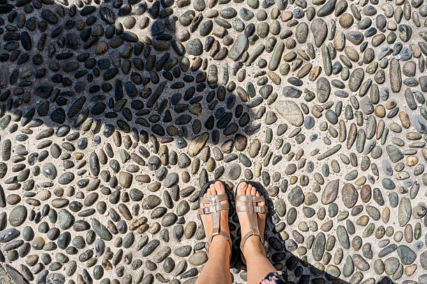 Female legs in elegant gold sandals on black background.