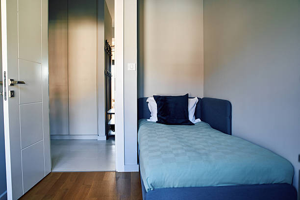 Serene Minimalist Bedroom Design Featuring a Cozy Single Bed Against a Softly Colored Wall with an Open Door Leading to a Bright Space