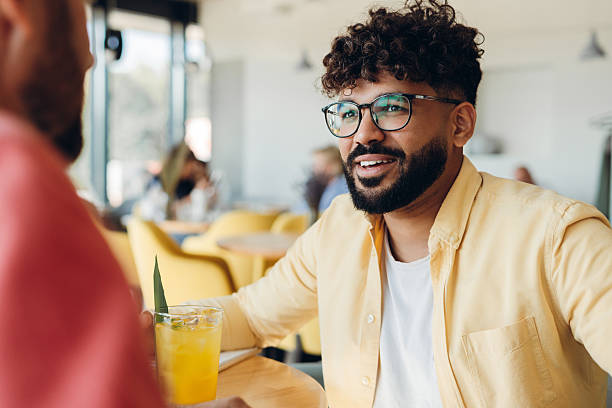 istock Handsome middle eastern man wearing eyeglasses talking with friend sitting in modern cafe 2249347528