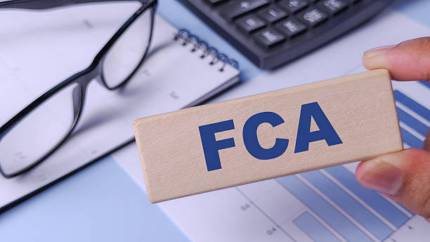istock FCA (Financial Conduct Authority) Concept: Wooden Block with Abbreviation Held Over Financial Chart, Calculator, and Notebook 2249353301