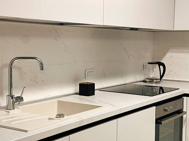istock Modern Kitchen with Marble Countertops Featuring Stainless Steel Sink, Electric Kettle, Induction Cooktop, and Minimalistic Design Elements 2249353515