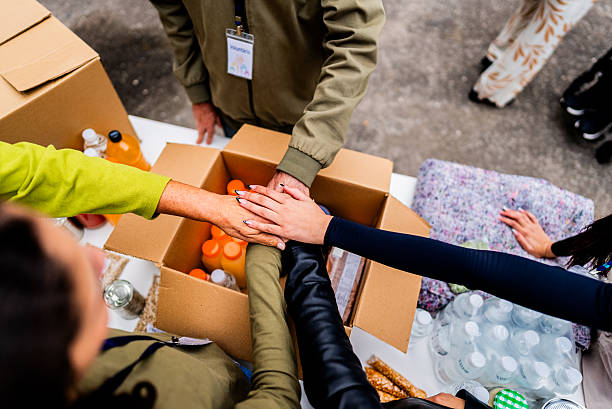 istock Volunteers stack their hands on top of a cardboard box during community donation effort 2249355117