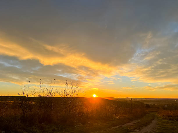 istock Sunset over fields and trees in a green hilly landscape under a colorful sky 2249355630