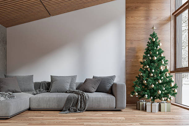 istock A cozy modern interior in a log cabin, with a decorated Christmas tree placed beside large windows with a snowy outdoor view, a gray sofa in front of an empty white wall and copy space 2249355921