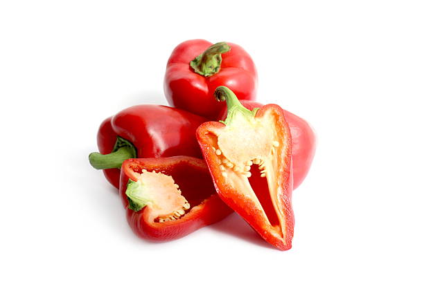 There is a pile of red sweet peppers lying on a white background.