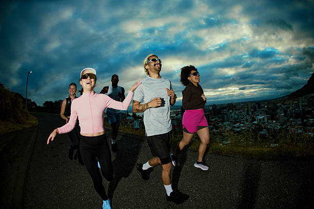 Group of diverse generation z people running uphill, enjoying morning exercise with cityscape view