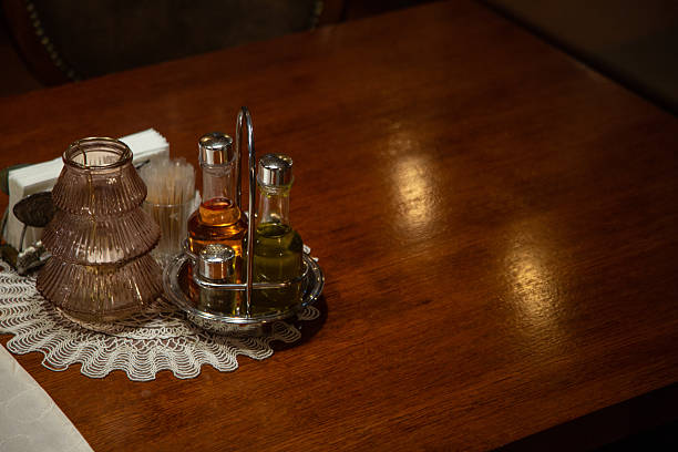 Restaurant table prepared for dining with condiments, doily, and wood surface