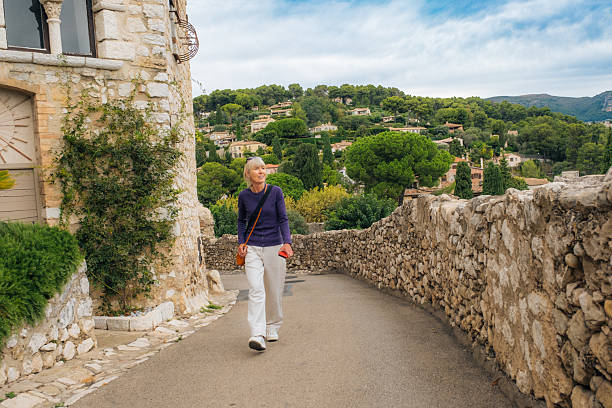 Senior woman enjoying an early morning stroll in the village of Saint Paul de Vence, Provence, France.