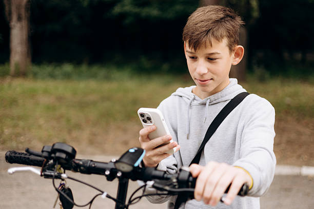 istock Teen boy outdoors riding an electric scooter while using a smartphone. 2249364968