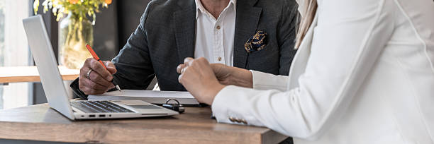 istock Business Meeting With Two Professionals Reviewing Documents Together At Table With Laptop 2249365611