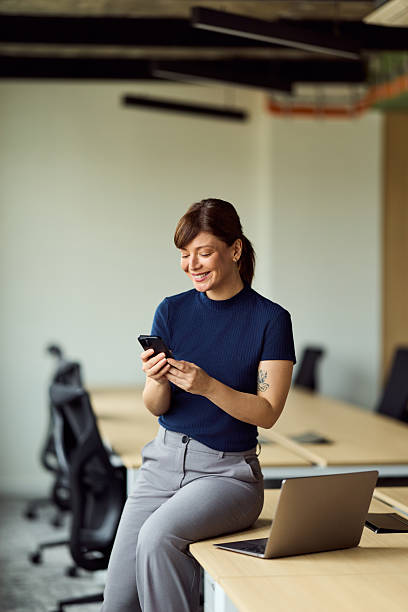 istock Professional Woman Using Smartphone In Modern Office With Laptop And Desk 2249367660